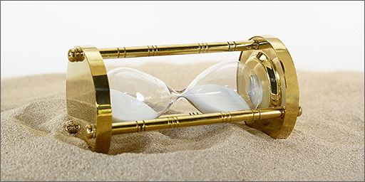 Image of hourglass lying on the sand - represents the idea of time passing.